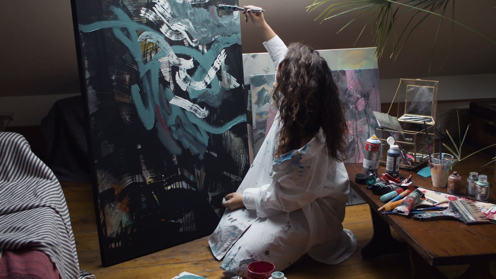 Artist painting expressive abstract art on a large canvas indoors.